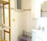 Bathroom has a sink, shelves, tub with shower