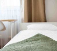 Close-up of bed with green blanket