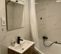 The bathroom has a sink and tub with a shower head and curtain
